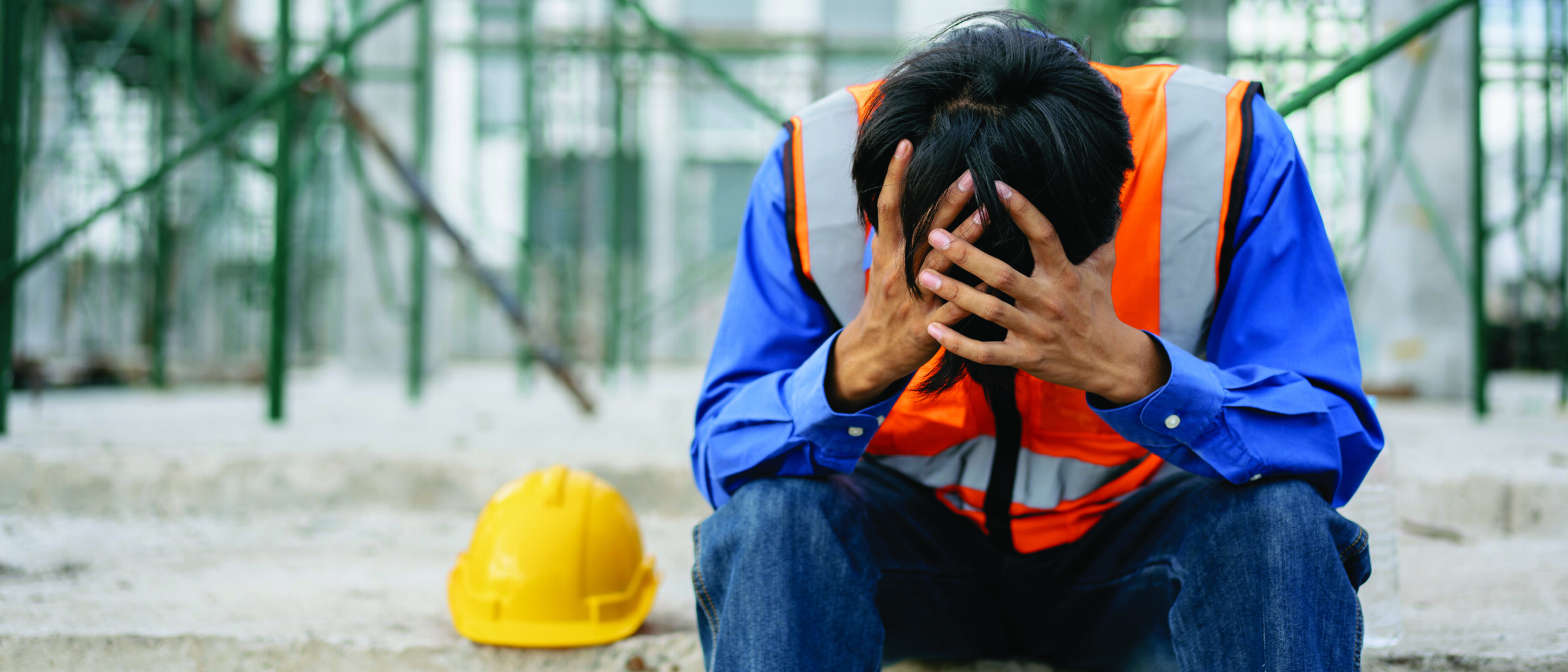 Foreman sitting hold the head with hands in factory construction site, tired fatigue exhaustion worker hard, suffering stress, upset, having problems as work, depression, have a headache, heat stroke